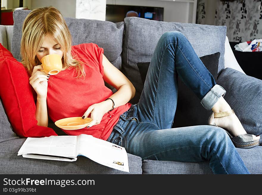 Beautiful blond woman having her morning coffee and reading her magazine