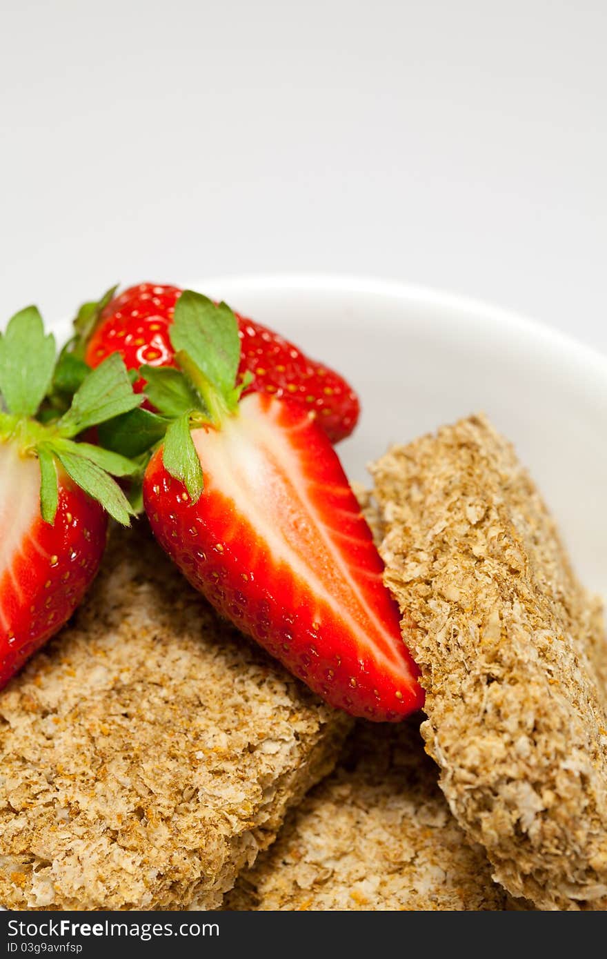 Sliced strawberries and wheat biscuits in a bowl.