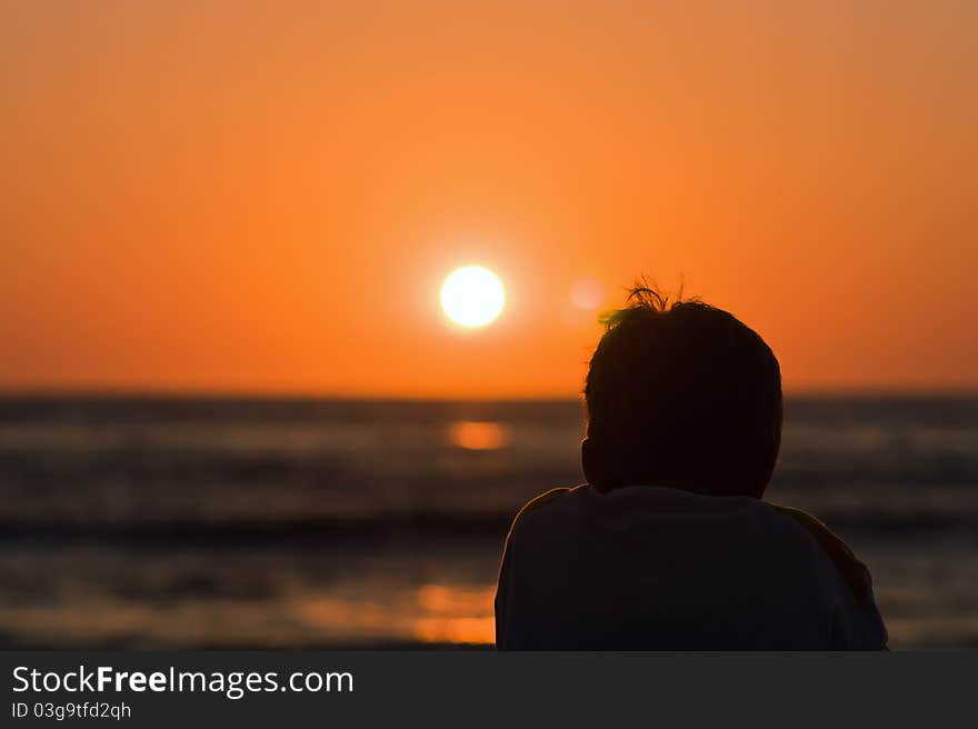 Silhouette of a boy watching sunset at the sea. Silhouette of a boy watching sunset at the sea