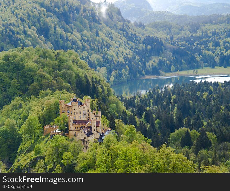 View of the medieval castle of Hohenschwangau and Alpsee lake on the background of the Alps. View of the medieval castle of Hohenschwangau and Alpsee lake on the background of the Alps