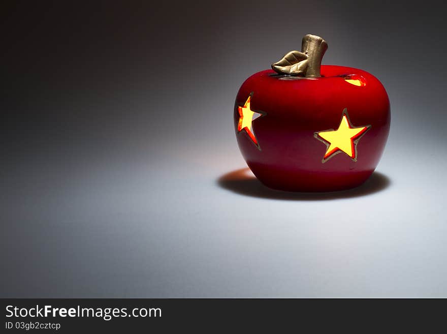 Decorative red apple with luminous stars c enigmatic illuminated from the top on black white background