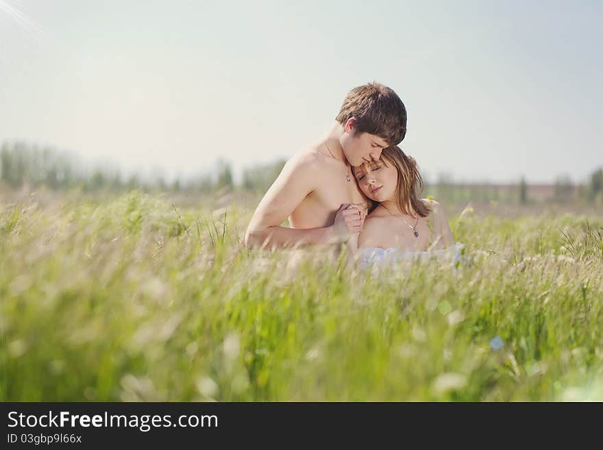 Beautiful young pair kissing and hugging on green grass