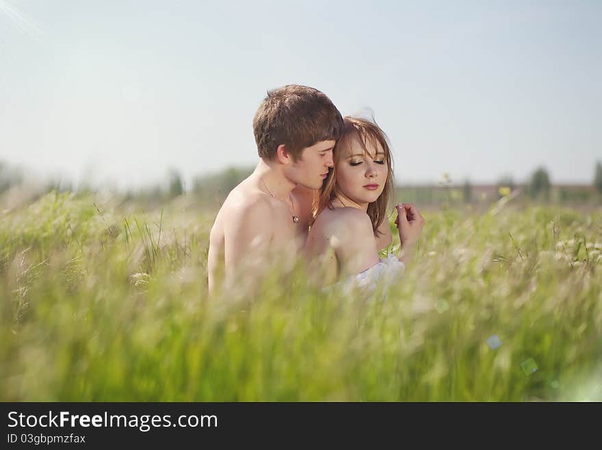 Beautiful young pair kissing and hugging on green grass