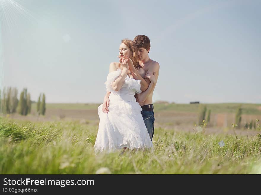 Beautiful young pair kissing and hugging on green grass