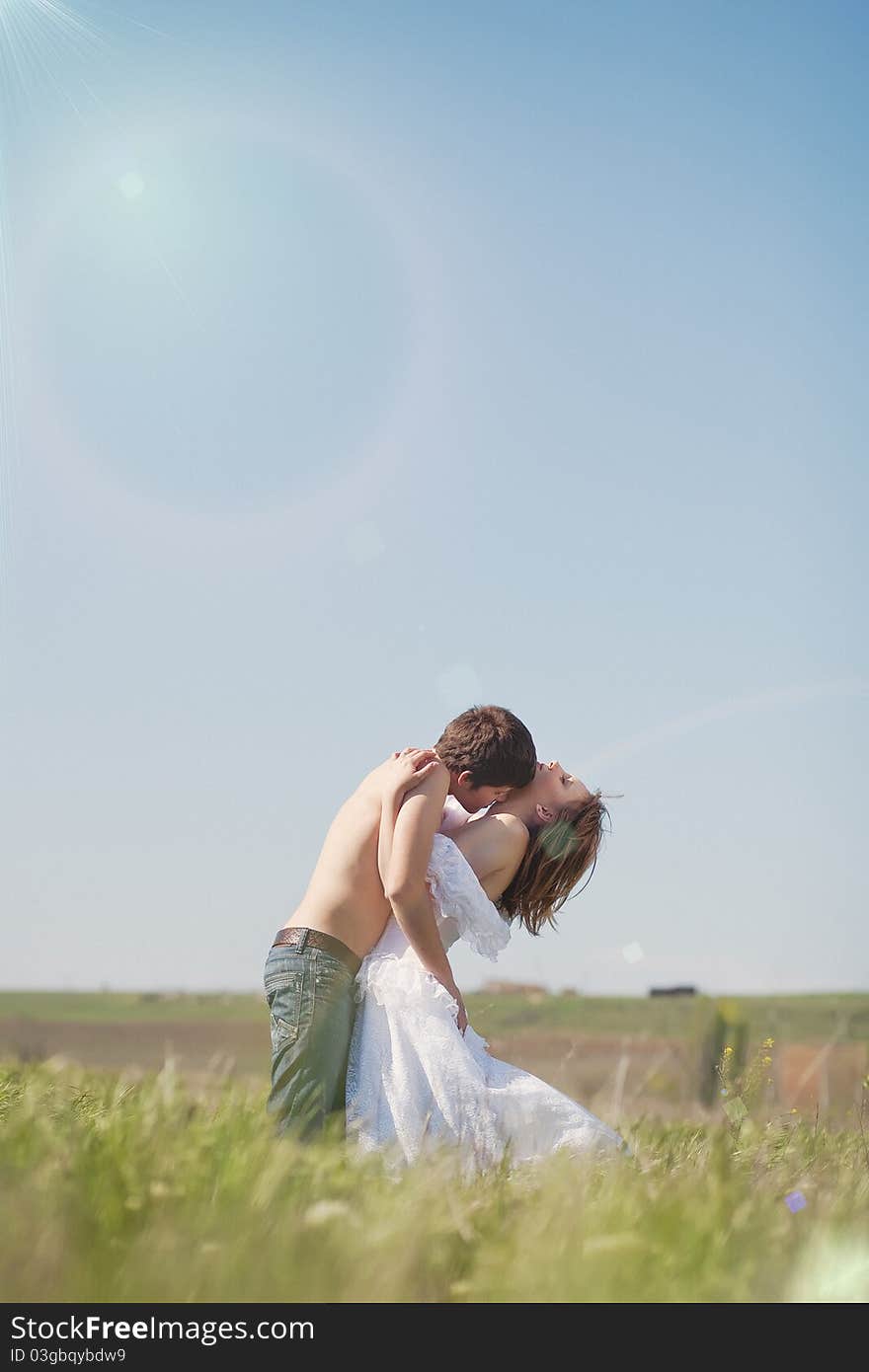 Beautiful young pair kissing and hugging on green grass