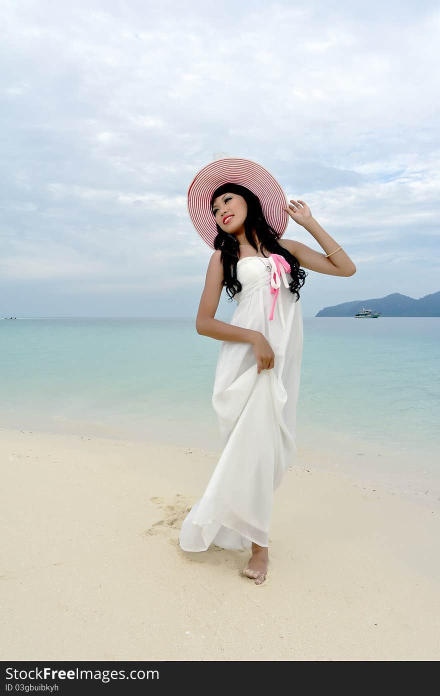 Young woman walks with hat on beach of tropical island during holiday. Young woman walks with hat on beach of tropical island during holiday