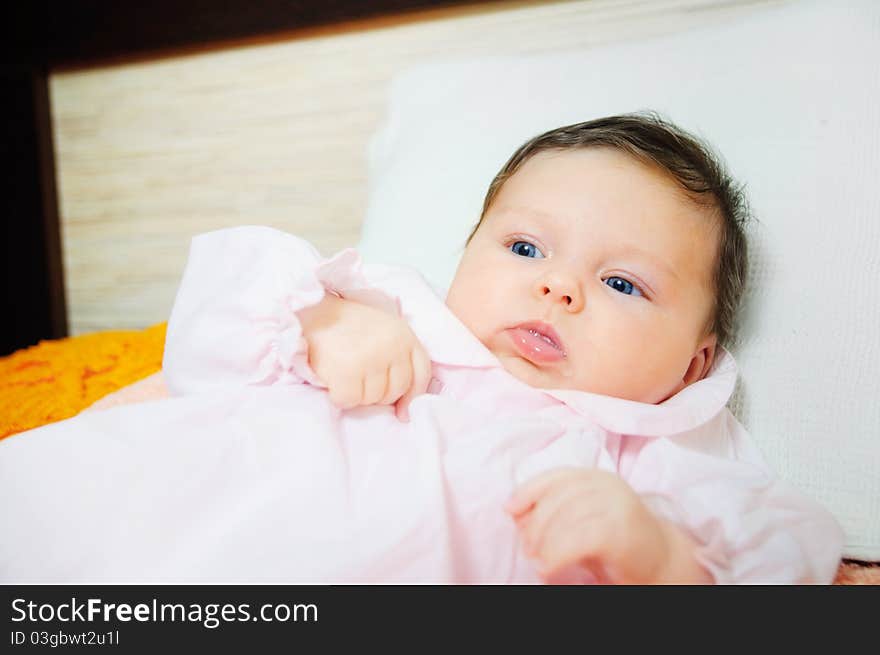 Beautiful baby girl is lying in a bed.