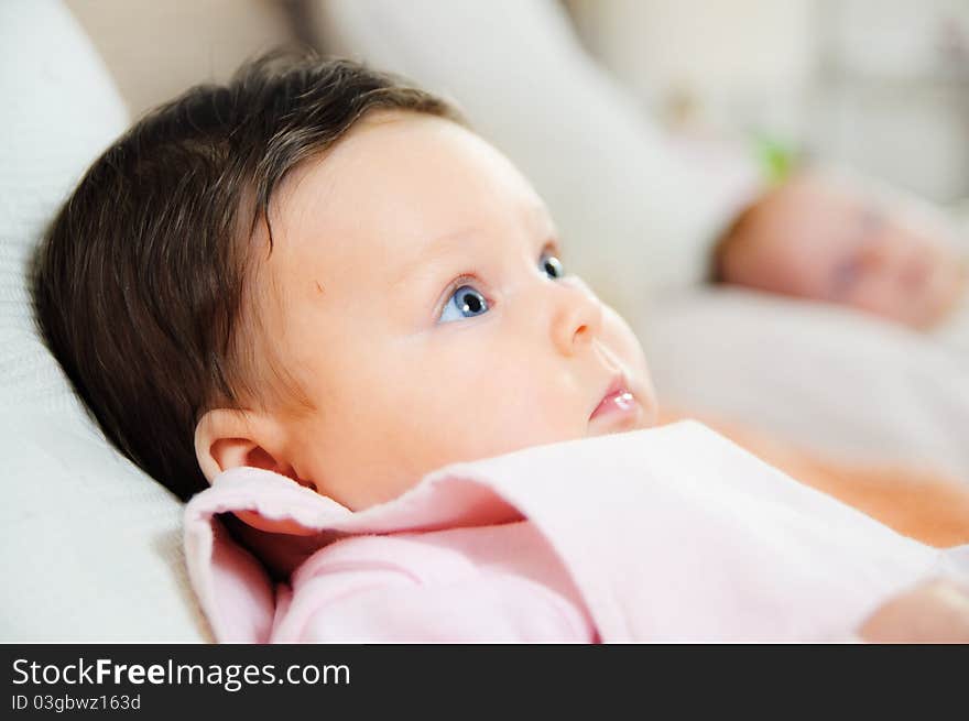 Beautiful baby girl is lying in a bed.