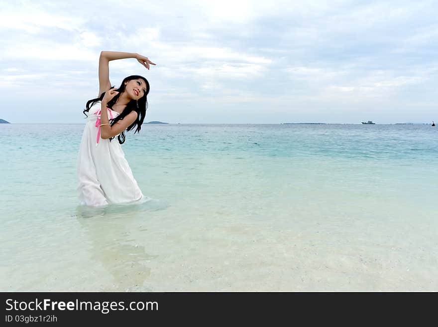 Young woman performs with raised hands on clear crystal beach of tropical island during holiday. Young woman performs with raised hands on clear crystal beach of tropical island during holiday