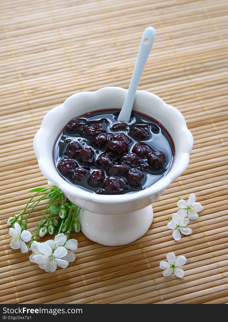 Cherry jam with white flowers on the bamboo napkin. Cherry jam with white flowers on the bamboo napkin.