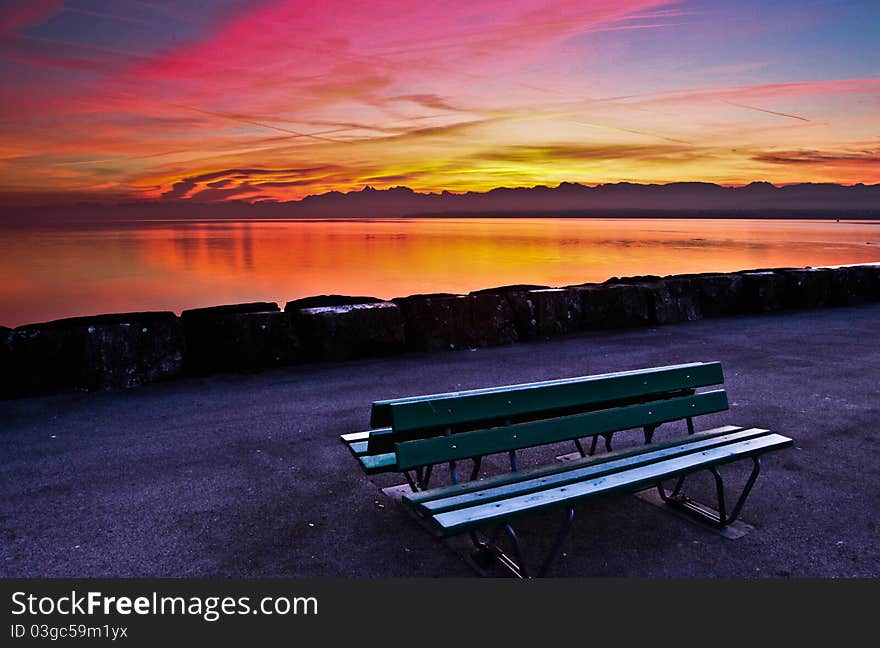 An interesting colors of early morning sky and a green bench. An interesting colors of early morning sky and a green bench