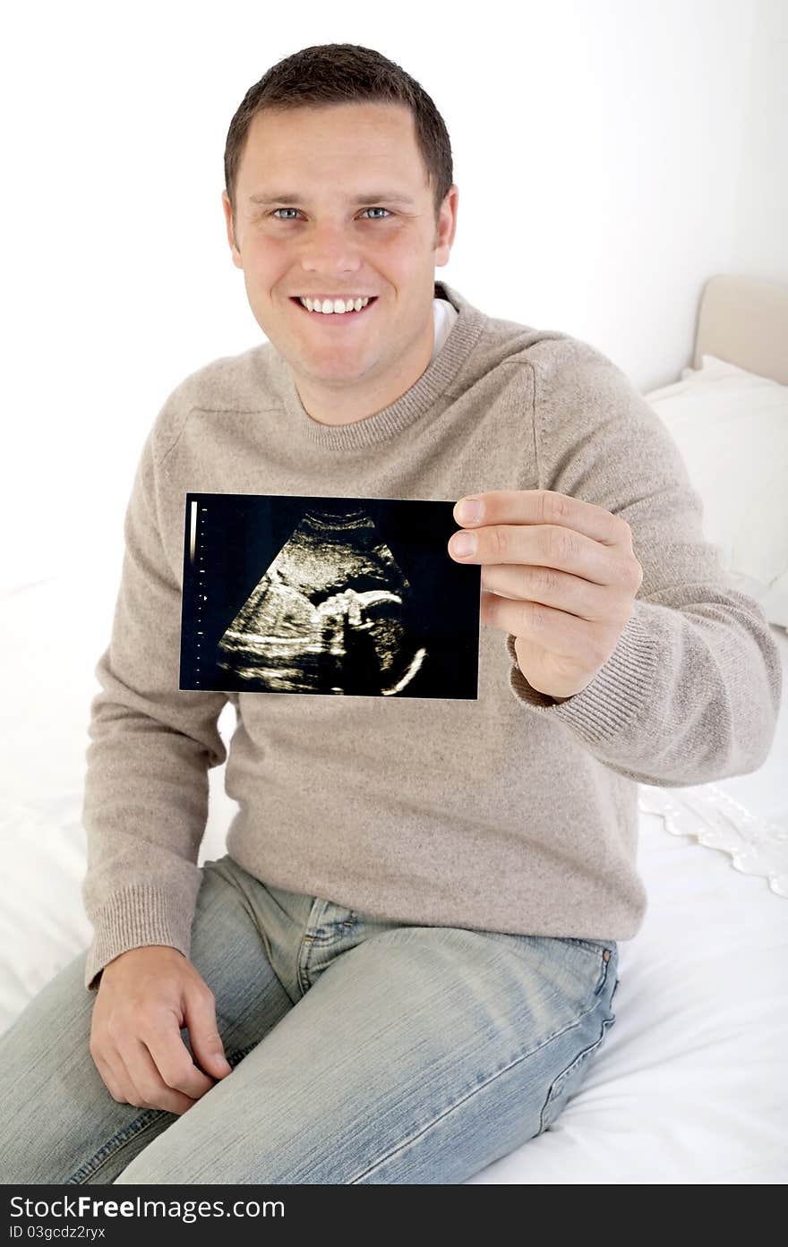 Proud dad holding ultrasound scan to camera (focus on scan)