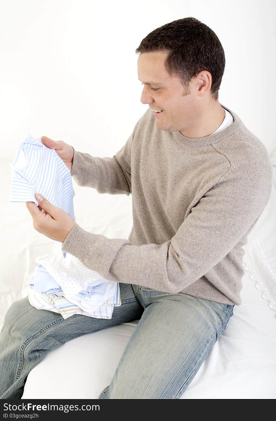 Happy dad looking at baby clothes. Happy dad looking at baby clothes