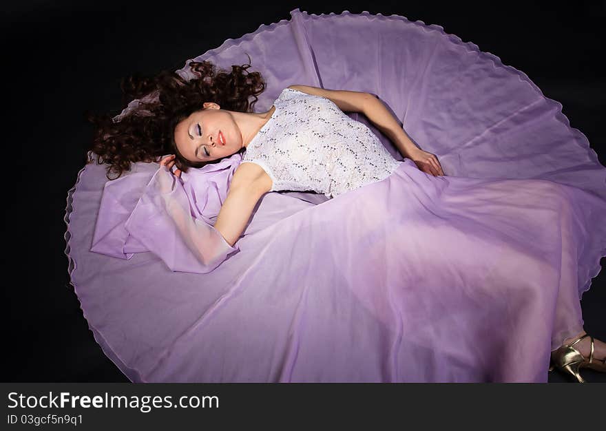 Attractive woman lying on the floor in liliac dress