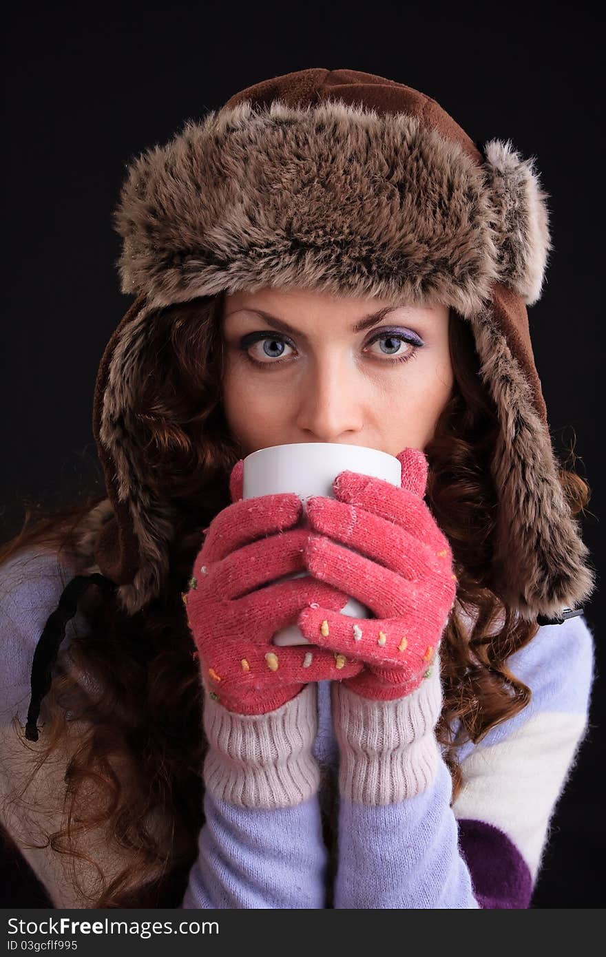 Romantic image of beautiful woman in a fur hat with a cup