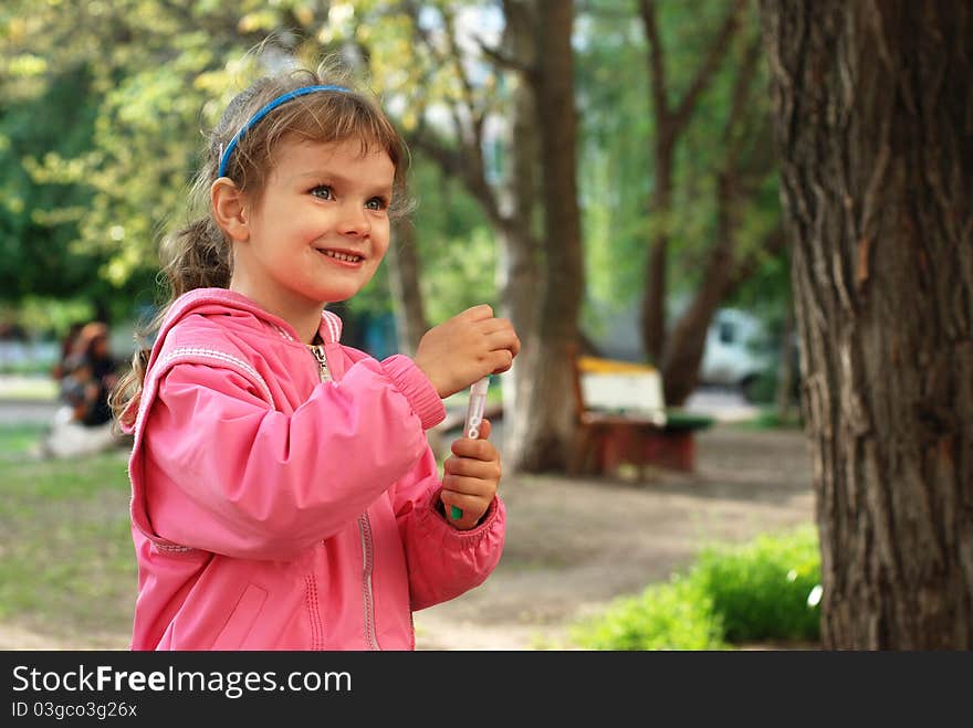 Spring in the city park. Little girl playing with bubbles