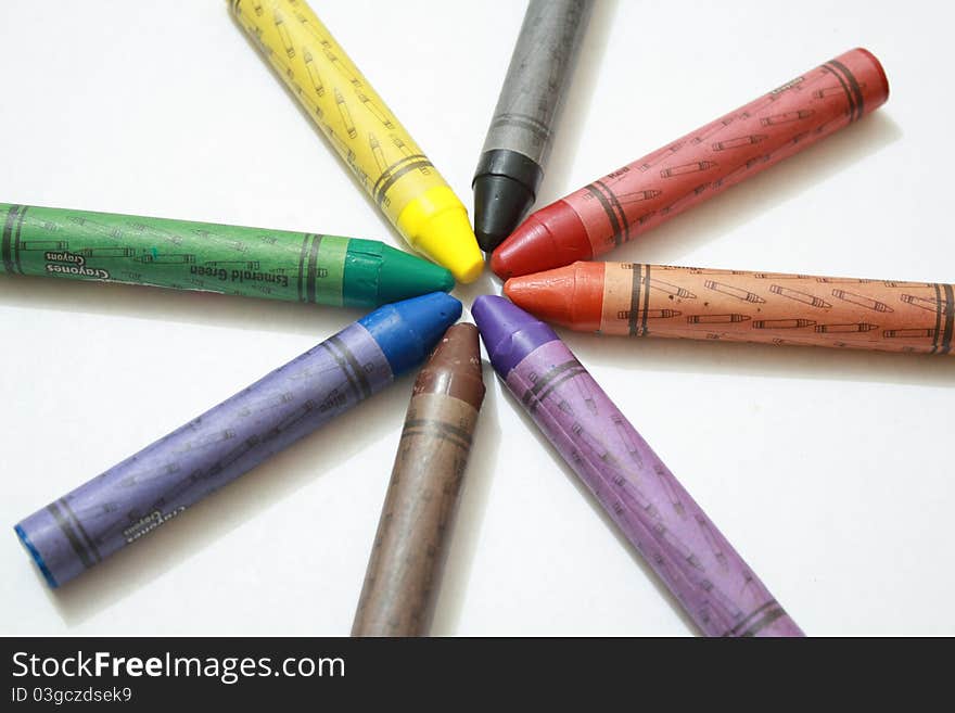 Eight crayons for kids, arranged in a circle shape.