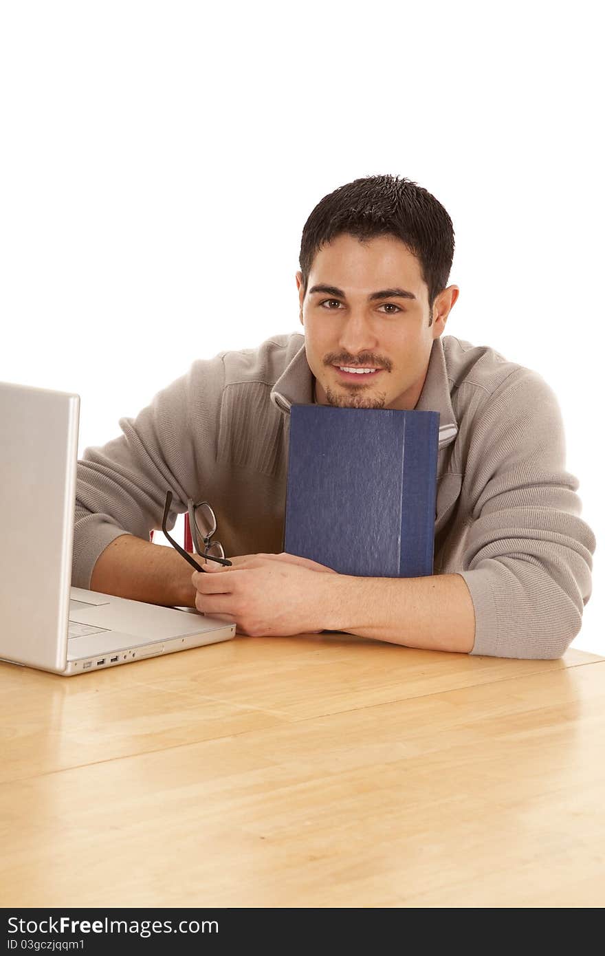 A student is sitting at a table leaning on a book. A student is sitting at a table leaning on a book.