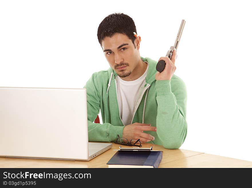 A man in green sitting at his table sick of studying by holding a gun and looking not happy. A man in green sitting at his table sick of studying by holding a gun and looking not happy.