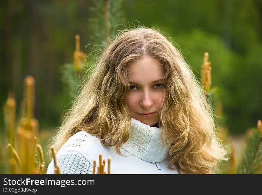 A young girl with long blond hair among young pines. A young girl with long blond hair among young pines