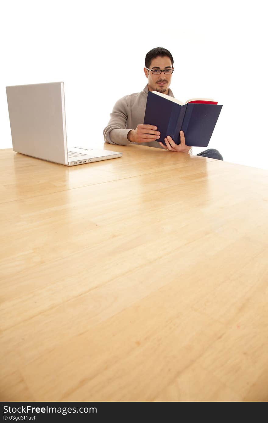 A man is sitting at a big table reading a book. A man is sitting at a big table reading a book.