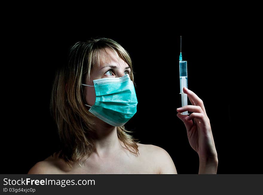 Young woman with a syringe on dark background