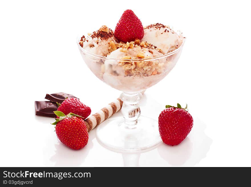 Ice cream with nuts and strawberry in a glass bowl over white