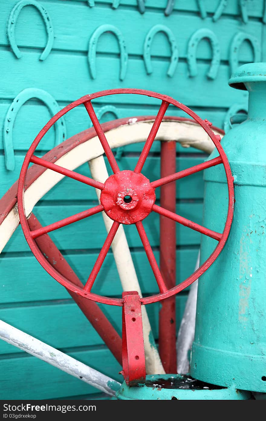 A detailed telephoto shot of a brightly painted wagon or carriage wheel with aqua painted horseshoes and wall in Nicaragua. A detailed telephoto shot of a brightly painted wagon or carriage wheel with aqua painted horseshoes and wall in Nicaragua.