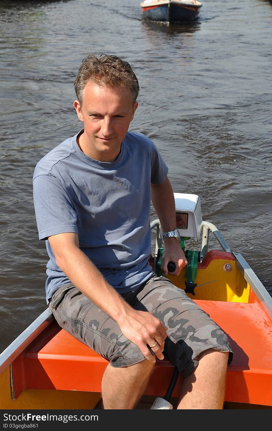 Boatman steering a small boat over the canal. Boatman steering a small boat over the canal