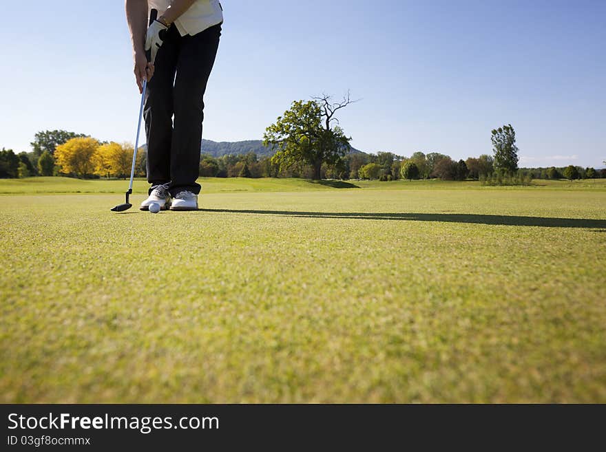 Female golf player putting ball.