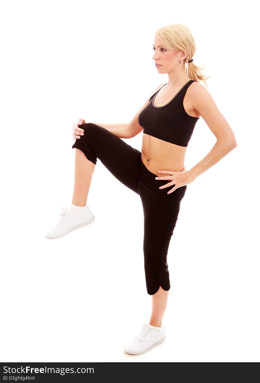 A young female dressed in black gym clothes performing a stretching exercise on isloated white background. A young female dressed in black gym clothes performing a stretching exercise on isloated white background