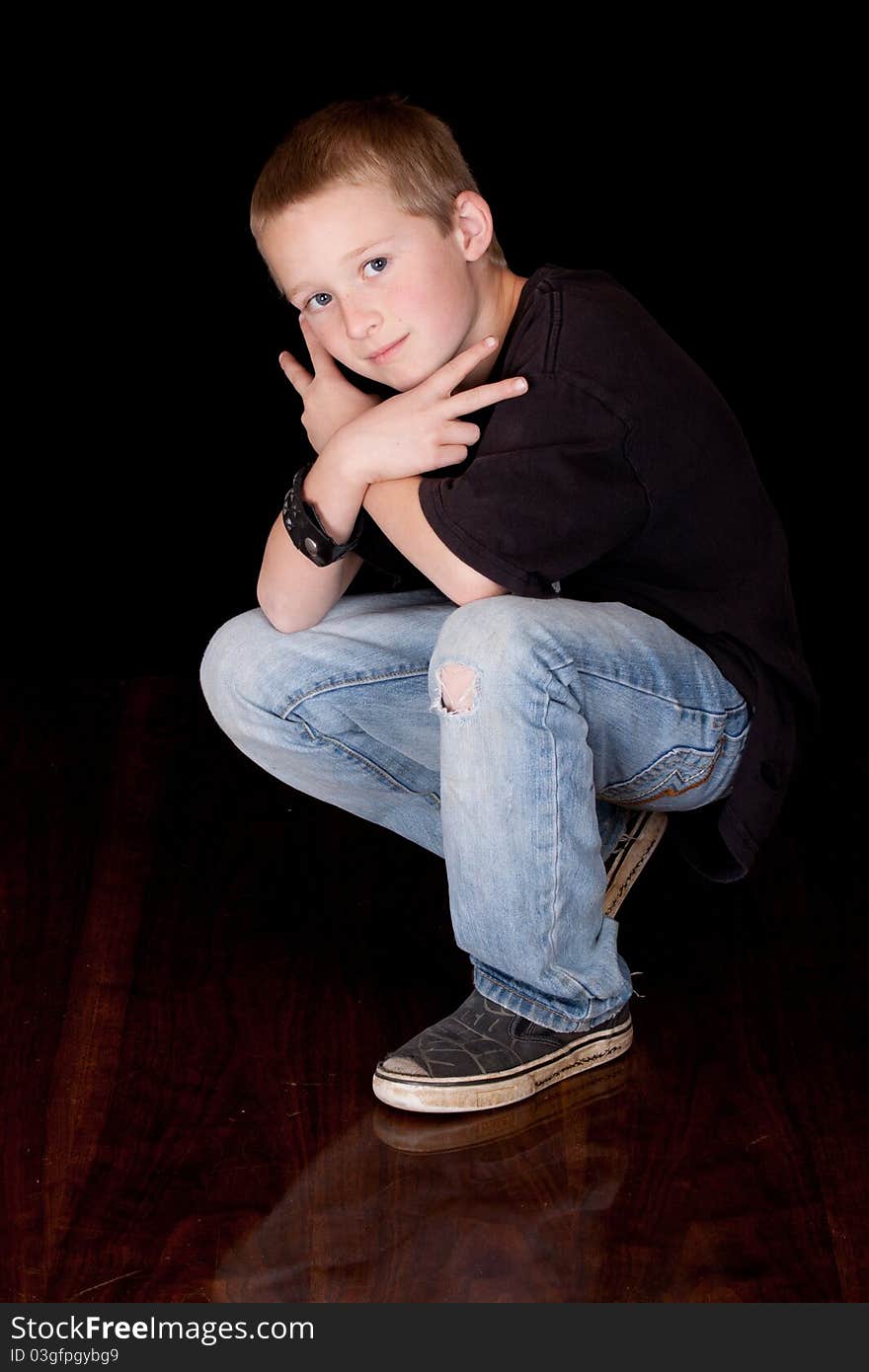 A photograph of a young boy with his arms crossed and his fingers in a peace sign.