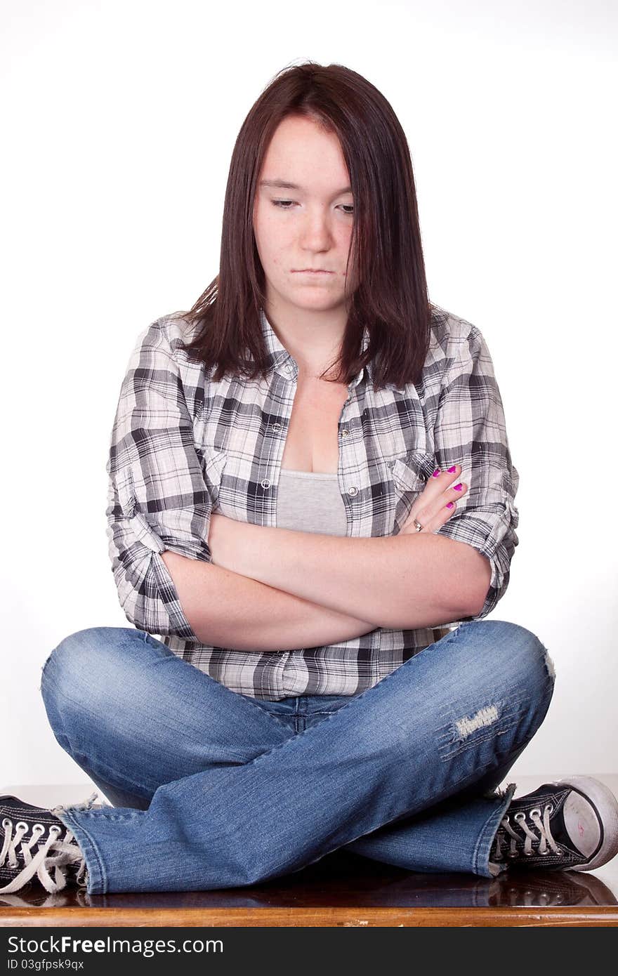 A photograph of a teenage girl sitting with her legs and arms crossed pouting. A photograph of a teenage girl sitting with her legs and arms crossed pouting.