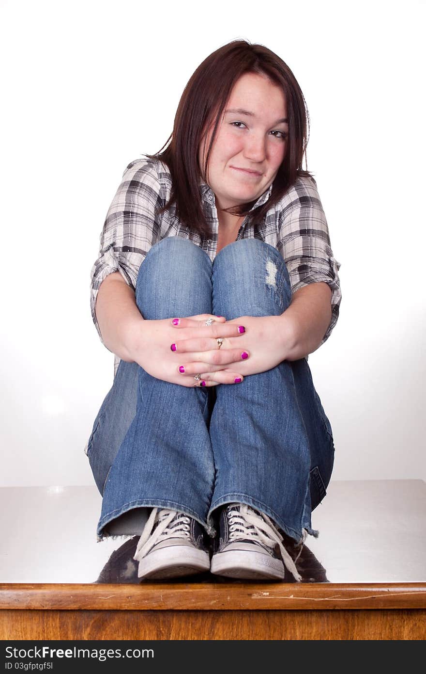 A photograph of a teenage girl with her legs up and hands folded with a smirk smile. A photograph of a teenage girl with her legs up and hands folded with a smirk smile.