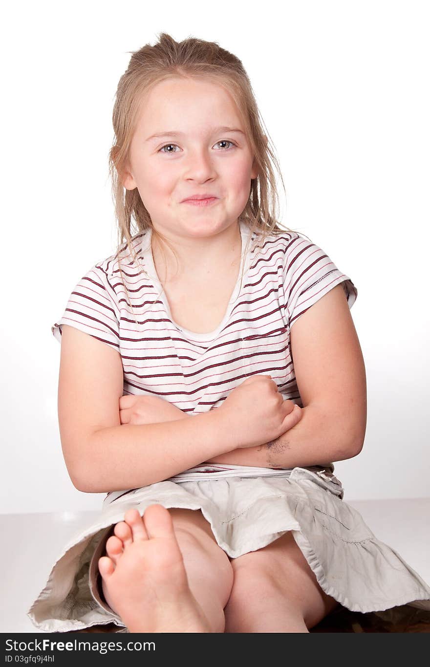 A photograph of a young girl with her arms crossed sitting on a desk trying not to smile. A photograph of a young girl with her arms crossed sitting on a desk trying not to smile.