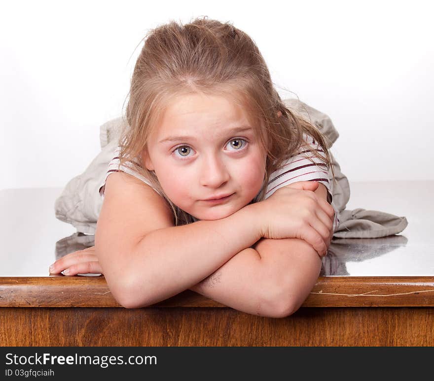 A photograph of a young girl lying on a desk looking forward with her big eyes. A photograph of a young girl lying on a desk looking forward with her big eyes.