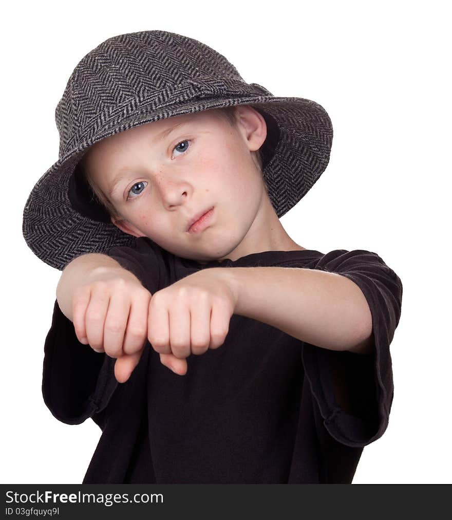 A photograph of a young boy with his knuckles showing while wearing his grey hat.