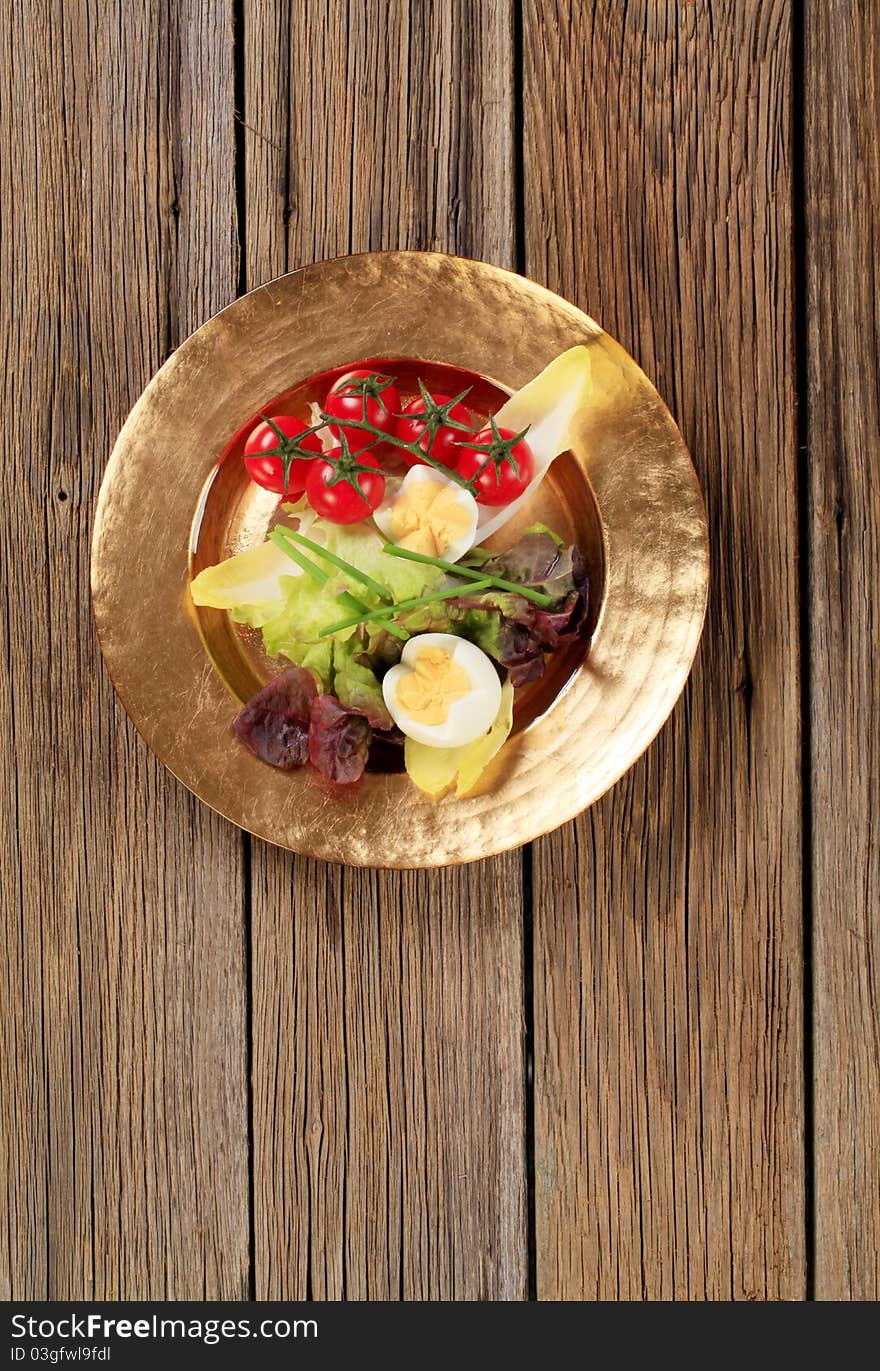 Fresh vegetables and boiled eggs on gold plate