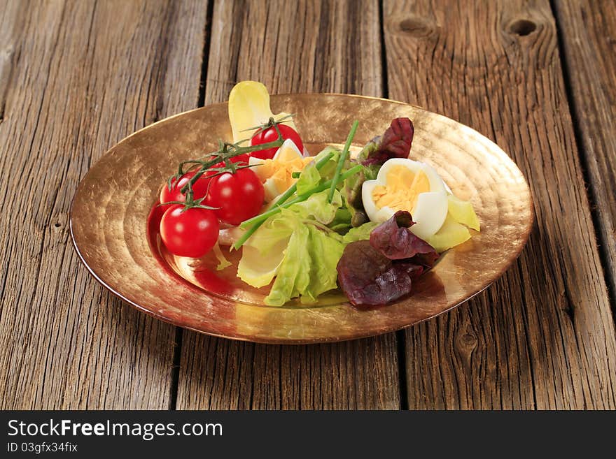 Fresh vegetables and boiled eggs on gold plate