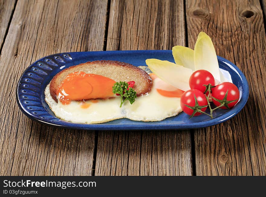 Fried egg and bread and vegetable garnish. Fried egg and bread and vegetable garnish