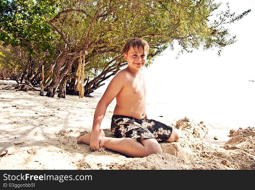 Happy young boy covered by fine sand at the beach. Happy young boy covered by fine sand at the beach