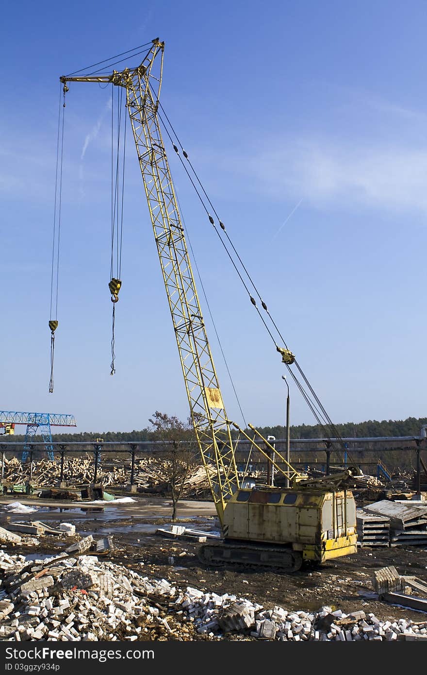 The small building crane which is standing near factory on processing of wood