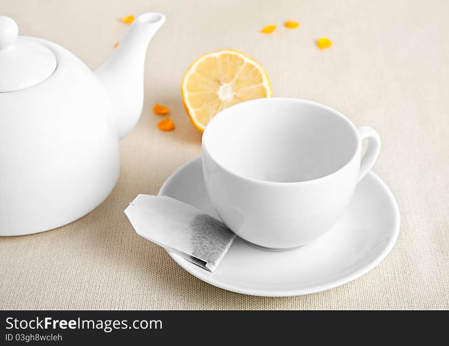 White cup with tea bag and teapot, on the table