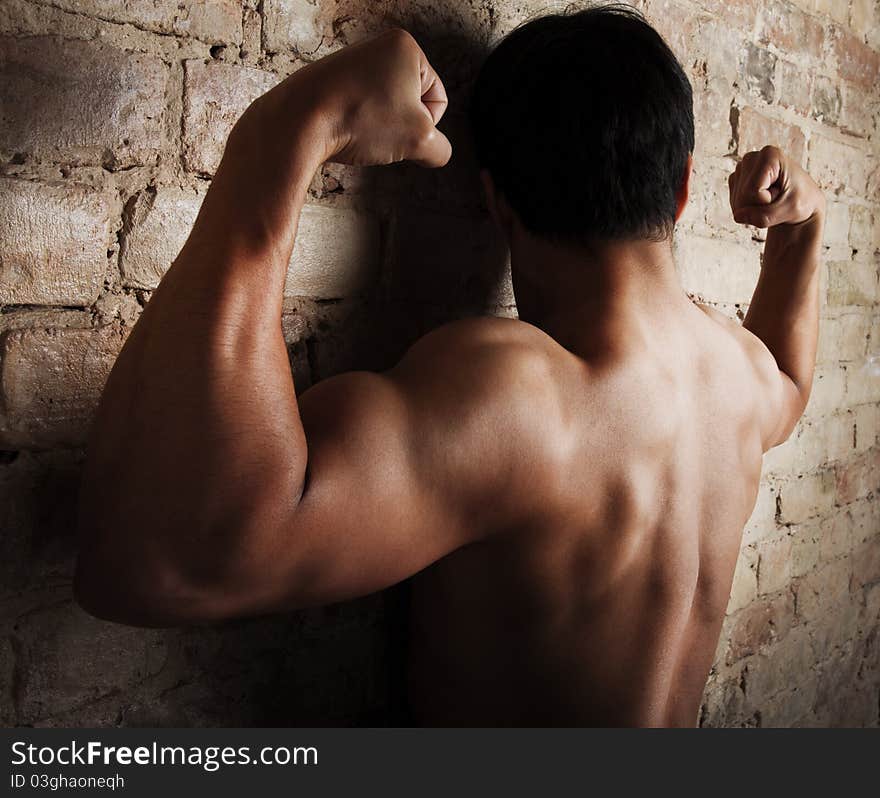 Handsome sportsman is posing near wall. Handsome sportsman is posing near wall