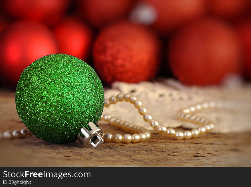 Red and green Christmas balls on an old vintage table with pearls