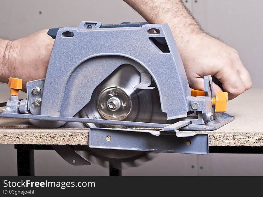 Close-up of a construction worker's hand and power tool while planing a piece of wood trim for a project. Close-up of a construction worker's hand and power tool while planing a piece of wood trim for a project.