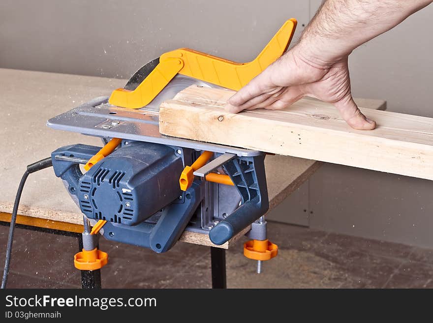 Close-up of a construction worker's hand and power tool while planing a piece of wood trim for a project. Close-up of a construction worker's hand and power tool while planing a piece of wood trim for a project.