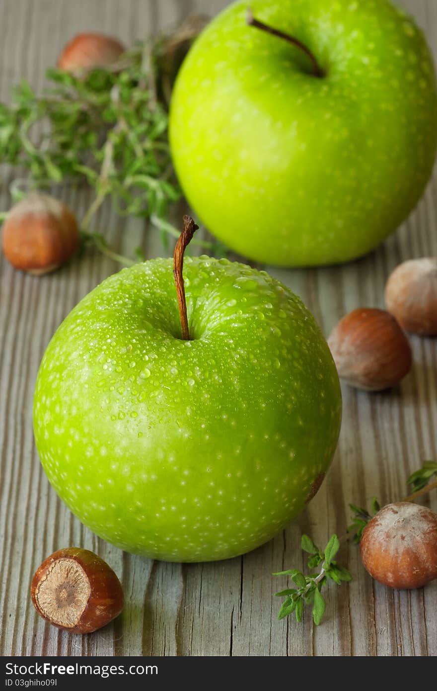 Green apples, hazelnuts and thyme in a morning garden.