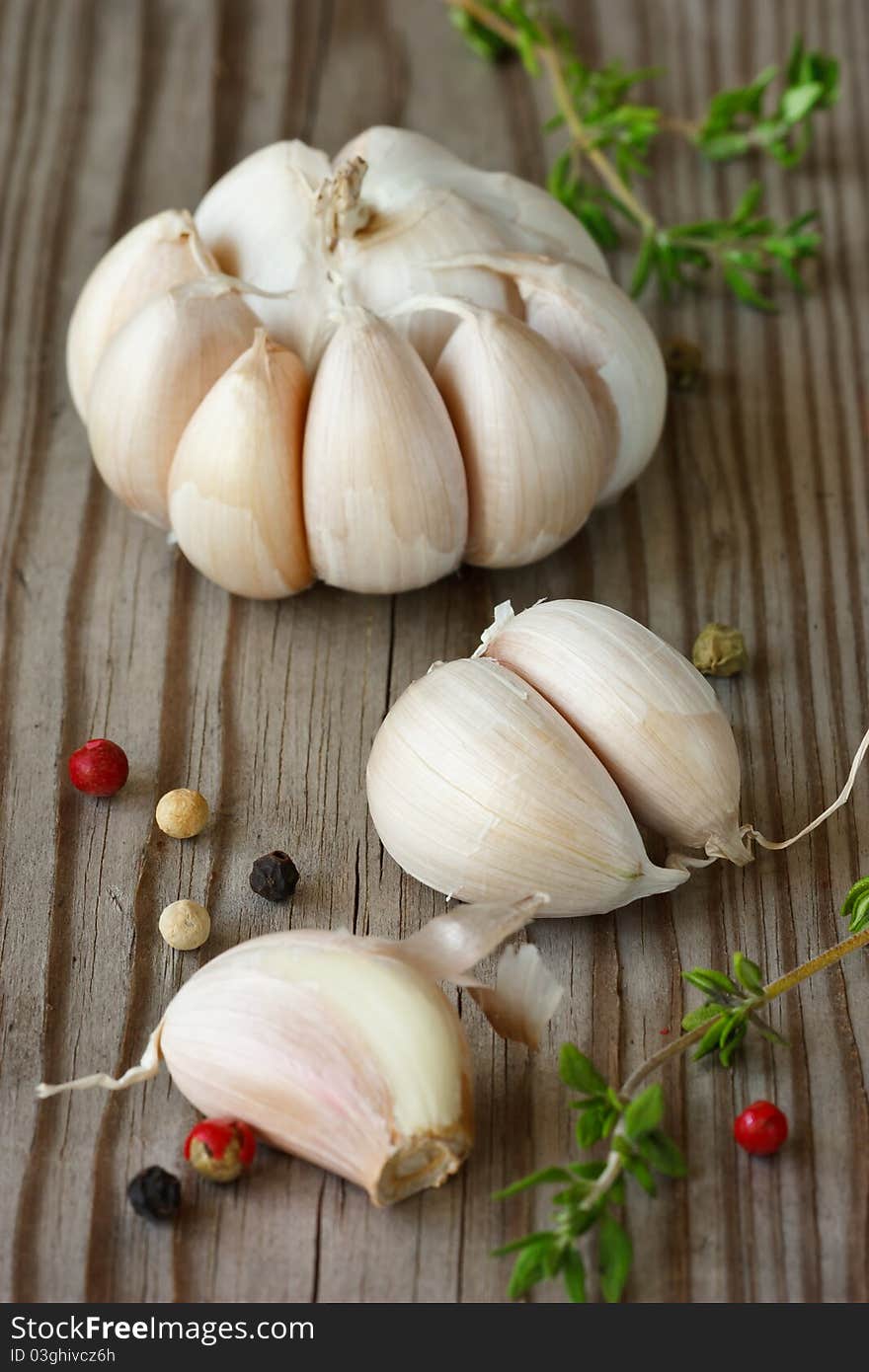 Garlic, colorful peppercorns and thyme on an old wooden board. Garlic, colorful peppercorns and thyme on an old wooden board.