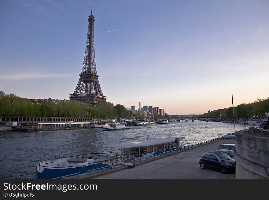 Eiffel Tower on the banks of the River Seine at sunset. Urban night landscape.